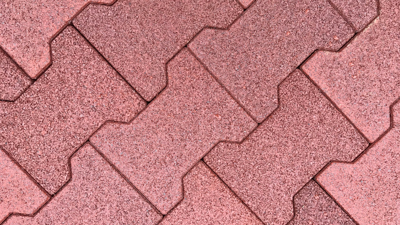 Red Interlocking dogbone-style rubber tiles placed on the ground.