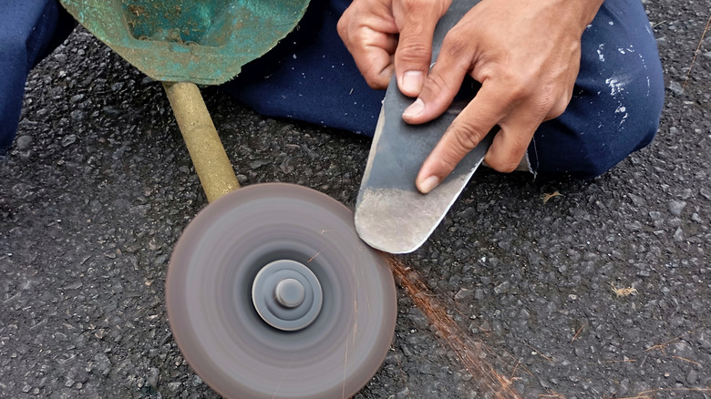 Grinding a metal blade with sparks flying