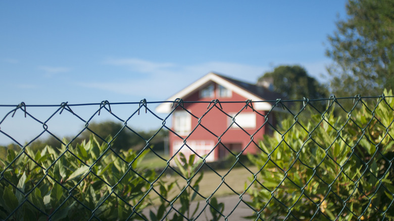A red house behind chain-linked fencing
