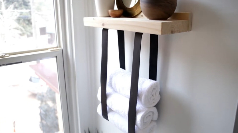 DIY shelf with leather straps holding rolled towels