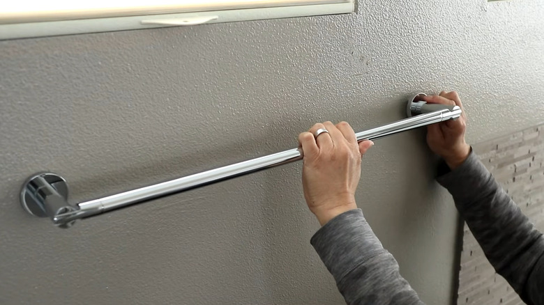 Person removing a towel rack from the wall