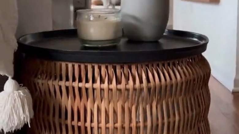 Tall wicker basket with a tray on top to create a makeshift storage side table
