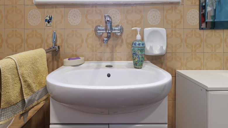 A giant basin sink takes up space in an outdated bathroom