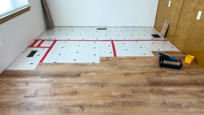 Wood flooring is installed over laminate in a kitchen