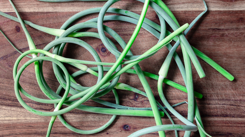 Green garlic scapes on a wooden cutting board