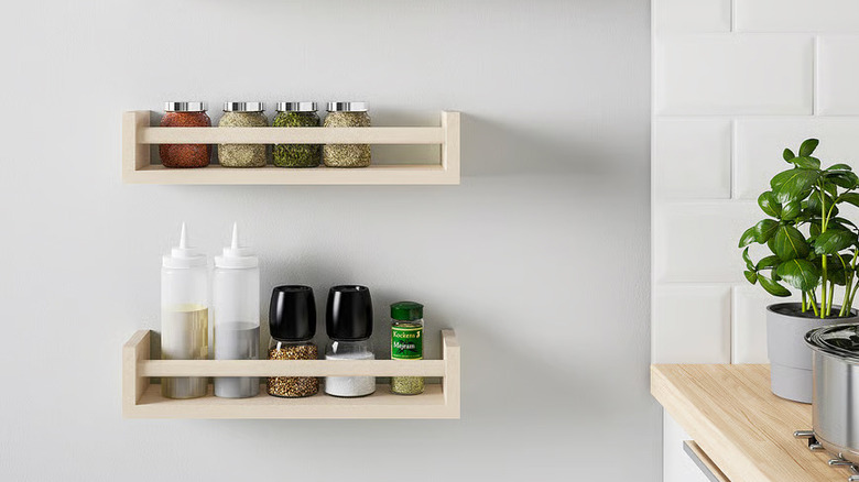 Two IKEA BEKVÄM Spice racks hanging on a wall next to a wooden kitchen countertop