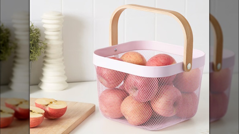 A pink IKEA RISATORP Wire basket is full of apples