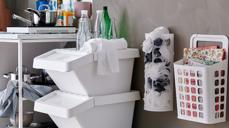 An IKEA VARIERA Plastic Bag Dispenser on a wall next to several white plastic storage containers