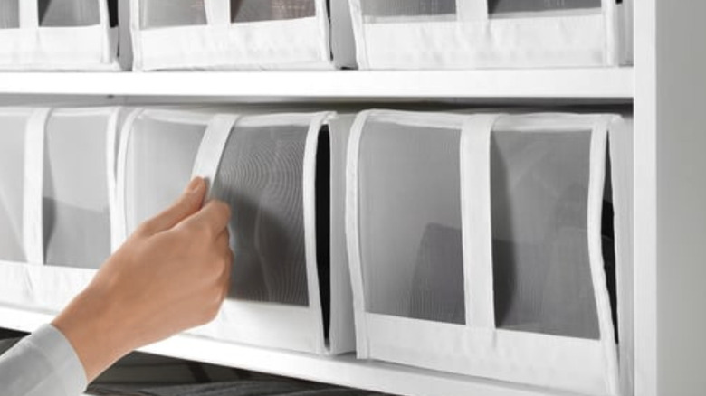 Person reaching for a fabric IKEA shoe box on a shelf.