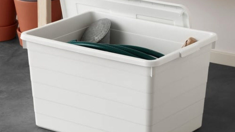 White plastic storage bin with a garden hose inside.