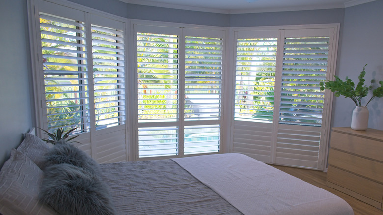 A bedroom with plantation shutters on the window.