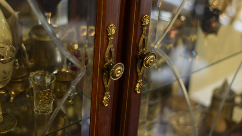 the door of a glass curio cabinet filled with glassware