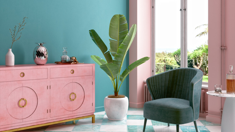 A vibrant room with pink cabinet, green chair, teal walls, and chequered floor