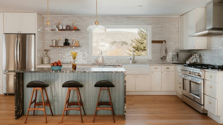 A modern white and teal kitchen with curved features like an island and barstool chairs