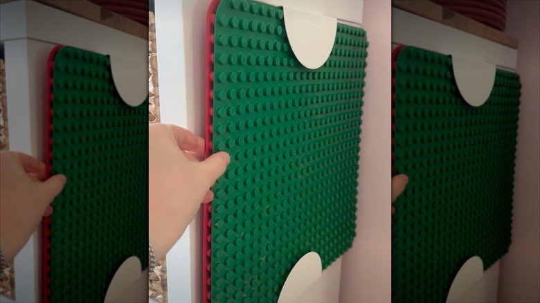 A person slides Lego mats into a low-profile storage channel created using two BEGRIPA handles from IKEA