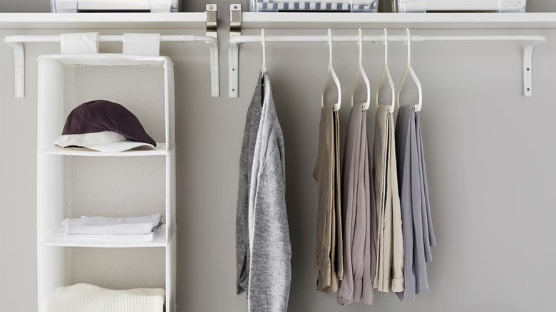 closet with clothes hanging in two rows on IKEA MULIG wall-mounted adjustable rod