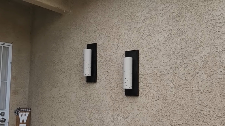 Two porch lights hang on a gray stucco wall