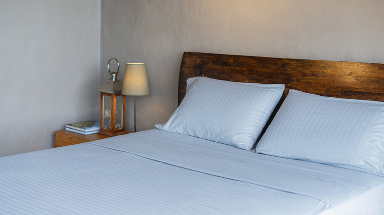 A closeup of a wooden bed dressed in a matching blue bedding set