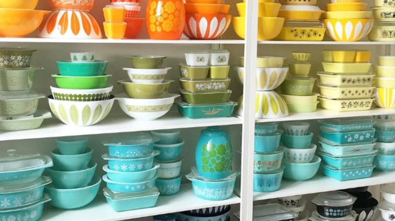 Colorful Pyrex and other vintage bowls arranged on shelves.