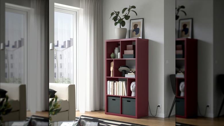 A brown-red KALLAX with differently spaced shelves full of decorative objects.