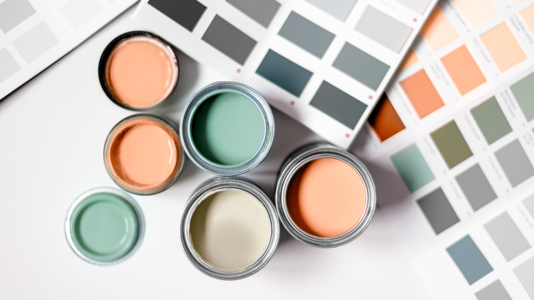 Open paint cans with paint sample cards on white surface.