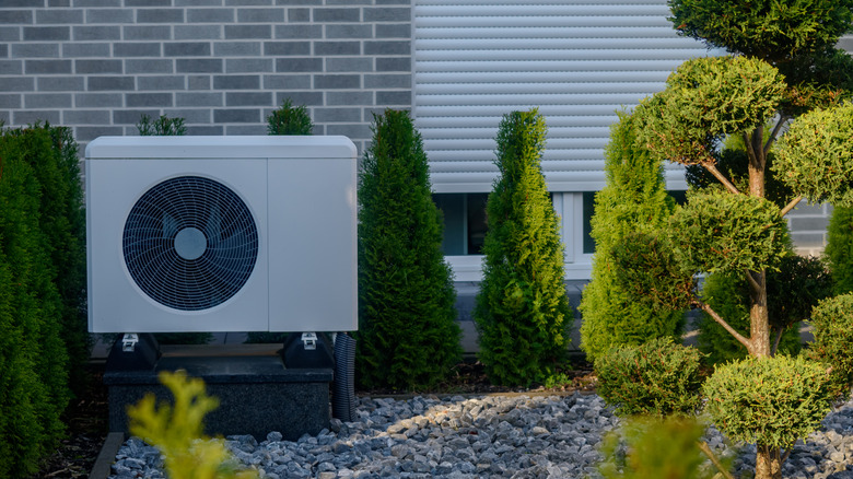 A heat pump sitting outside a home with modern, clean landscaping.
