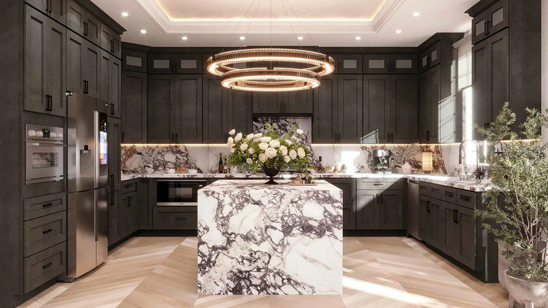 A modern light fixture illuminates veined marble countertops and dark gray kitchen cabinets