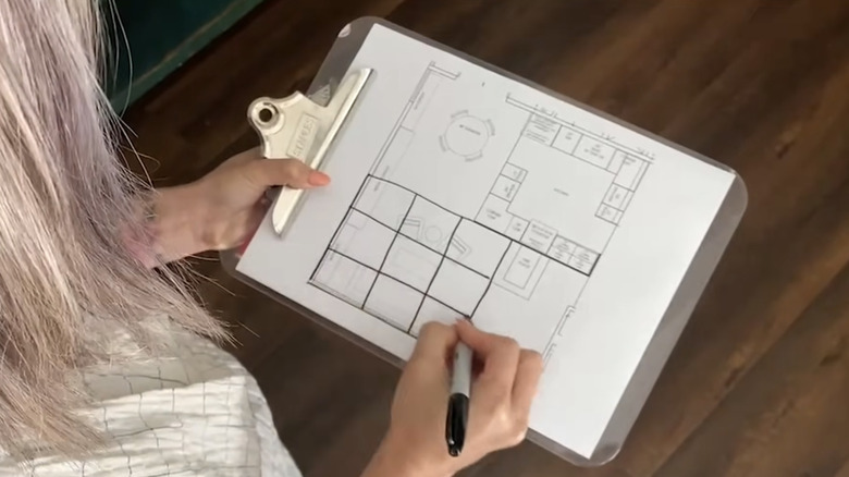 woman drawing nine sections on a floor plan of her living room to determine Feng Shui