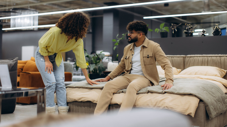 A smiling couple shops for a new mattress