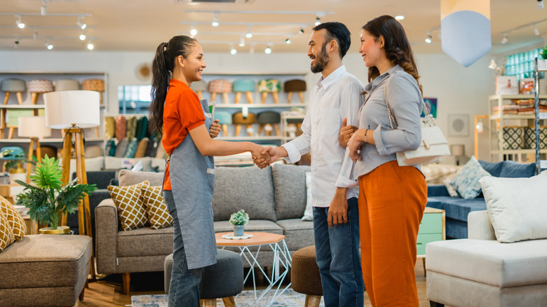 A young couple shakes hands with a furniture salesperson
