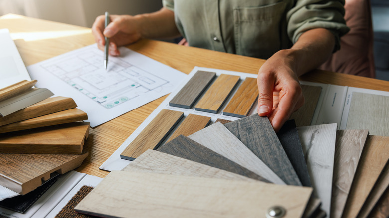 person with blueprints choosing floor samples