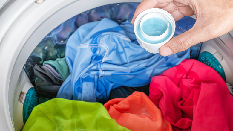 A hand with detergent washing colorful clothes