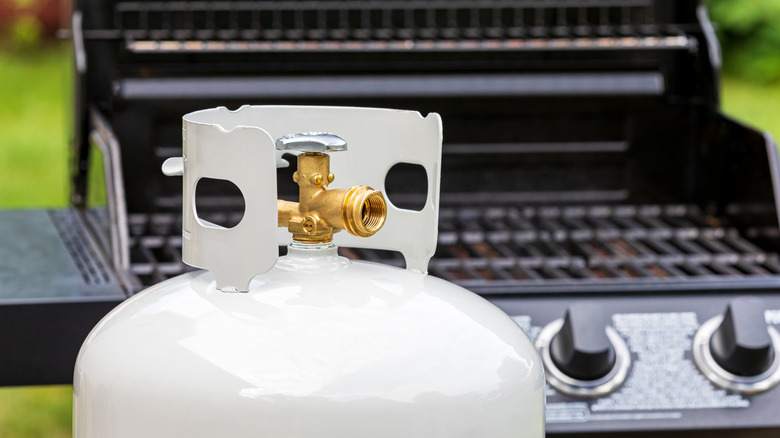 A propane tank and gas grill in sunlight