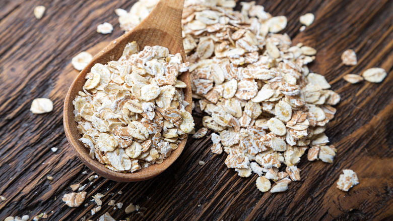 Rolled oats in wooden spoon on table