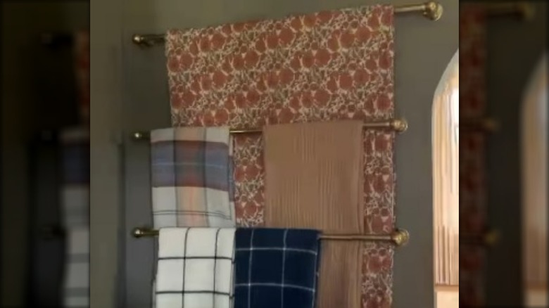 Blankets hung on curtain rods on wall