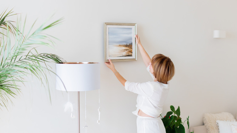 Woman hanging a photo of the beach in a silver frame