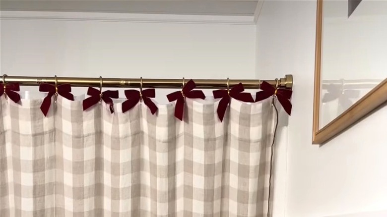 Red ribbons tied to shower curtain hooks in bathroom