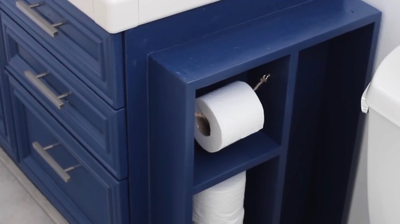 DIY toilet paper cabinet attached to sink cabinet, both painted blue.