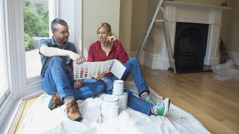 couple sitting on living room floor choosing paint color