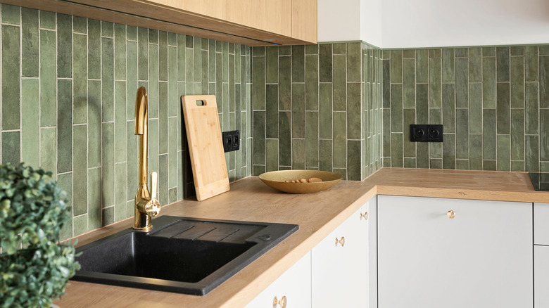 A kitchen with an olive green tile backsplash with color variation and vertical offset orientation