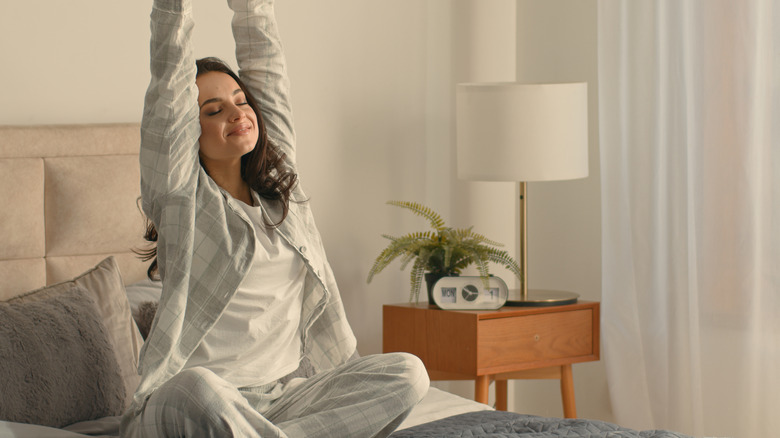Woman smiling while stretching on her bed