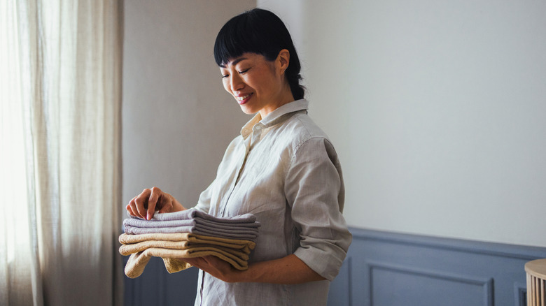A woman holds microfiber cloth towels stacked on one another