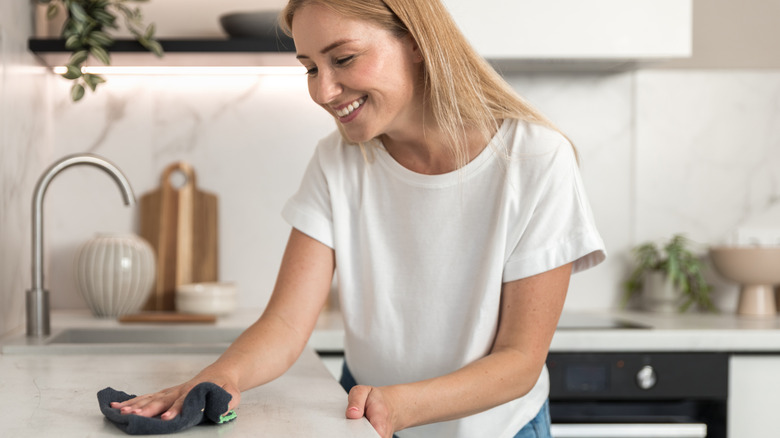 A woman wipes a kitchen surface with a cloth