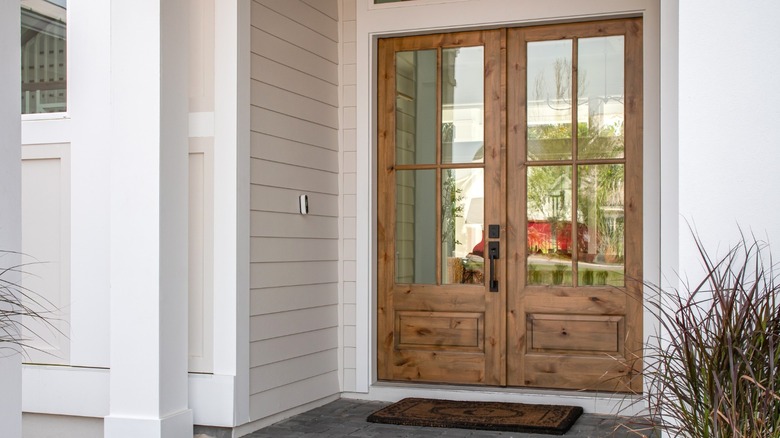 A wood front door with large windows on it with no decor or privacy elements