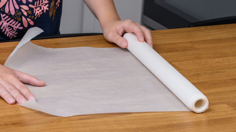 Person rolling out white paper on a wood table