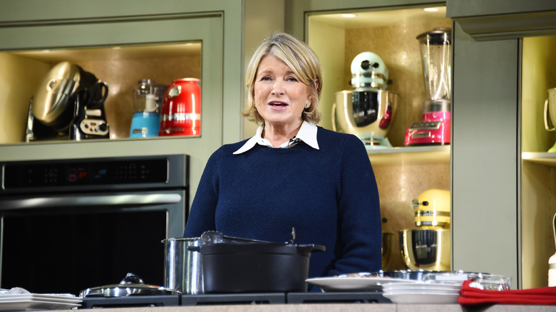 Martha Stewart wearing a blue sweater and standing in a kitchen