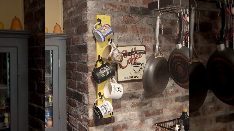 A yellow mug rack installed on a brick wall in a kitchen