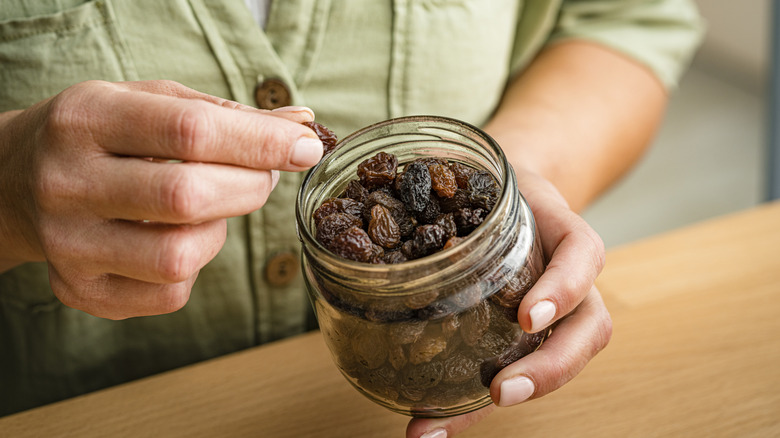 Person with raisins in a glass jar