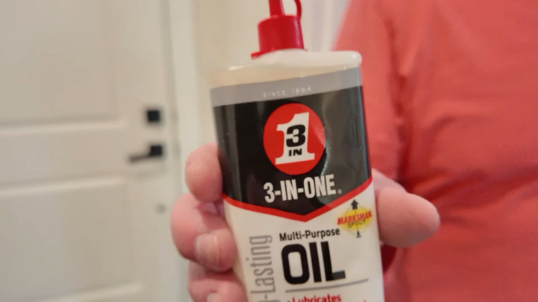 A man holding a bottle of 3-IN-ONE multipurpose oil