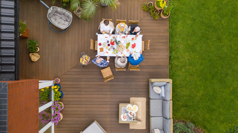 An overhead view of people sitting at table on a large, outdoor residential deck.